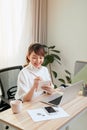 Beautiful young Asian woman writing notebook while working with laptop at home Royalty Free Stock Photo