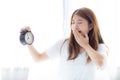 Beautiful young asian woman yawn wake up in morning annoyed alarm clock holding hand Royalty Free Stock Photo