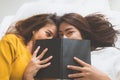 Beautiful young asian women LGBT lesbian happy couple kiss and smiling while lying together in bed under book at home. Royalty Free Stock Photo