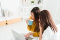 Beautiful young asian women LGBT lesbian happy couple sitting on bed hug and using laptop computer while drinking hot coffee cup. Royalty Free Stock Photo