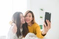 Beautiful young asian women LGBT lesbian happy couple sitting on bed hug and using phone taking selfie together bedroom at home.