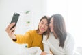 Beautiful young asian women LGBT lesbian happy couple sitting on bed hug and using phone taking selfie together bedroom at home. Royalty Free Stock Photo