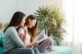 Beautiful young asian women LGBT lesbian happy couple sitting on sofa reading book together near window in living room at home. Royalty Free Stock Photo