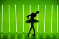 Beautiful young ballerina dancing classical ballet in a dark studio against a background of bright green neon lights Royalty Free Stock Photo