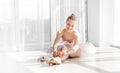 Young ballet dancer in tutu sitting on the floor and tying pointe shoes Royalty Free Stock Photo