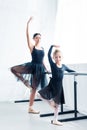 beautiful young ballet teacher and cute little student dancing together