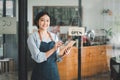 Beautiful young barista woman in apron holding order paper and standing in front of the door Royalty Free Stock Photo