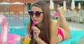 Beautiful young bikini woman in summer drinking a cocktail. Girl relaxing in tropical swimming pool. Portrait of young Royalty Free Stock Photo