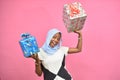 beautiful young black lady holding gift boxes and presents smiling and feeling excited, in front of pink background Royalty Free Stock Photo