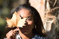 beautiful young black latin woman in a black and white dress leaning against the trunk of a tree and covering her eye and face Royalty Free Stock Photo