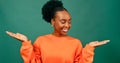 Beautiful young Black woman holds palms up weighing up choice, green studio Royalty Free Stock Photo