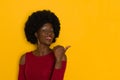 Beautiful Young Black Woman Is Pointing At Yellow Wall With Thumb Royalty Free Stock Photo