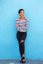 Beautiful young black woman smiling against blue wall in striped shirt Royalty Free Stock Photo