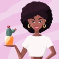 Beautiful young black woman in white shirt holding a cactus. Confident girl with afro hair and gold earrings on pink background