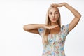 Beautiful young blond girl framing her face, put head in hand box and making silly face, posing against white background Royalty Free Stock Photo