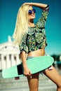 Beautiful young blond model girl in summer hipster clothes with skateboard Royalty Free Stock Photo