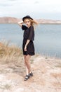 Beautiful young blond woman in a black dress and a light black hat in the desert and the wind blowing her hair in a hot summer day Royalty Free Stock Photo