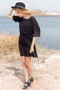 Beautiful young blond woman in a black dress and a light black hat in the desert and the wind blowing her hair in a hot summer day Royalty Free Stock Photo