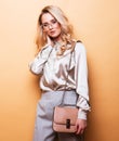 Beautiful young blond woman in a blouse and pants wearing sunglasses, holding handbag Royalty Free Stock Photo