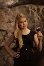 Beautiful young blond woman drinks wine in wine cellar Royalty Free Stock Photo