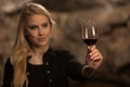 Beautiful young blond woman drinks wine in wine cellar Royalty Free Stock Photo