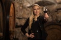 Beautiful young blond woman drinks wine in wine cellar Royalty Free Stock Photo