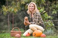 Beautiful young blond woman in her garden harvesting pumpkins