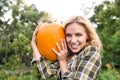 Beautiful young blond woman in her garden harvesting pumpkins