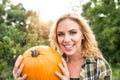 Beautiful young blond woman in her garden harvesting pumpkins