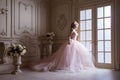 Beautiful young blond woman in luxurious long pink dress posing in vintage room interior