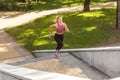 Beautiful young blond woman running up stairs with concentrated motivated expression, doing cardio training in park Royalty Free Stock Photo