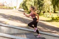 Beautiful young blond woman running up stairs with concentrated motivated expression, doing cardio training in park Royalty Free Stock Photo