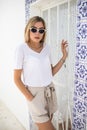 Beautiful young blond woman standing at the wall covered with portuguese traditional tiles azulejo.