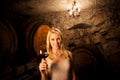 Beautiful young blond woman tasting red wine in a wine cellar Royalty Free Stock Photo