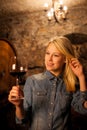 Beautiful young blond woman tasting red wine in a wine cellar Royalty Free Stock Photo