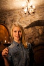 Beautiful young blond woman tasting red wine in a wine cellar Royalty Free Stock Photo