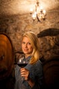 Beautiful young blond woman tasting red wine in a wine cellar Royalty Free Stock Photo