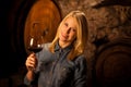 Beautiful young blond woman tasting red wine in a wine cellar Royalty Free Stock Photo