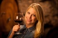 Beautiful young blond woman tasting red wine in a wine cellar Royalty Free Stock Photo