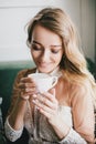 Beautiful young blond woman in a white dress enjoying coffee cappuccino with foam Royalty Free Stock Photo