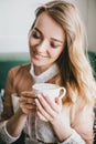 Beautiful young blond woman in a white dress enjoying coffee cappuccino with foam Royalty Free Stock Photo