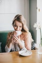 Beautiful young blond woman in a white dress enjoying coffee cappuccino with foam Royalty Free Stock Photo