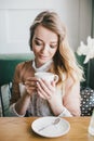 Beautiful young blond woman in a white dress enjoying coffee cappuccino with foam Royalty Free Stock Photo