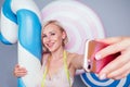 Beautiful young blonde Barbie sweet woman confectioner sexy model perfect makeup hug a huge lollipop with measuring tape Royalty Free Stock Photo