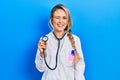 Beautiful young blonde doctor woman holding stethoscope winking looking at the camera with sexy expression, cheerful and happy Royalty Free Stock Photo