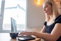 Beautiful young blonde female student using portable laptop computer while sitting in a vintage coffee shop.Young Royalty Free Stock Photo