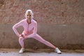 Beautiful young blonde fitness woman wearing pink sports clothes stretching and warming up legs in morning. Sporty woman Royalty Free Stock Photo