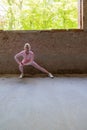 Beautiful young blonde fitness woman wearing pink sports clothes stretching and warming up legs in morning. Sporty woman Royalty Free Stock Photo