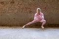 Beautiful young blonde fitness woman wearing pink sports clothes stretching and warming up legs in morning. Sporty woman Royalty Free Stock Photo