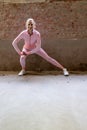 Beautiful young blonde fitness woman wearing pink sports clothes stretching and warming up legs in morning. Sporty woman Royalty Free Stock Photo